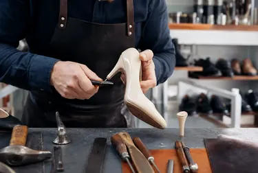 Profissional realizando a troca de salto em sapatos.